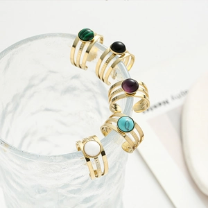 Detailed view of five gold multi-layer rings with colorful natural stone inlays on glass