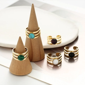 Detailed close-up of layered gold rings featuring colorful natural stones on wooden stands