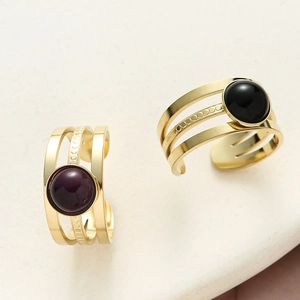 Detail of triple-layer gold open rings featuring purple and black round natural stones
