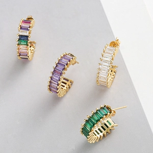 Détail de quatre boucles d'oreilles C dorées ornées de pierres précieuses colorées