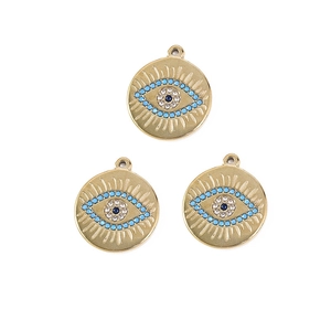 Detailed view of three gold evil eye charms with blue stones and crystals for DIY jewelry