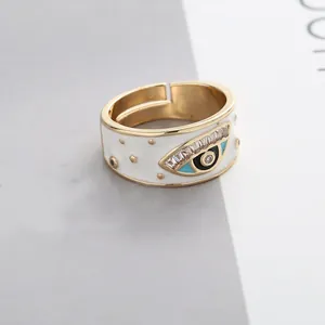 Detailed close-up of gold evil eye ring with white enamel and sparkling zircon stones