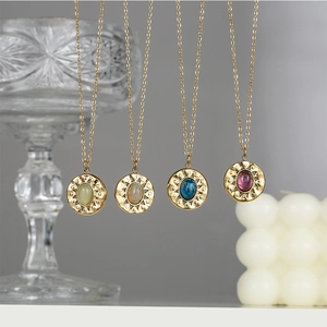 Detail of four gold sunburst pendant necklaces featuring colorful oval natural stones