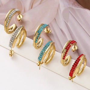 Detail of cross-layered C-shaped stud earrings set with red, blue and white rhinestones