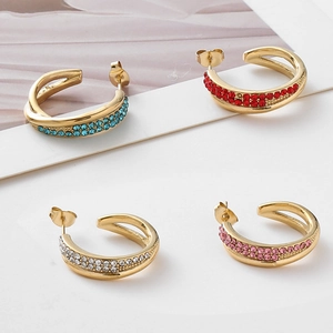 Macro detail of gold-plated C-shaped earrings with colorful sparkling rhinestone inlay
