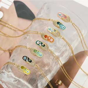 Détail de pendentifs capsule œil protecteur en émail coloré sur chaînes dorées