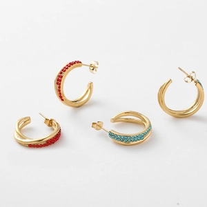 Detail of gold C-shaped earrings with rows of red and light blue rhinestones