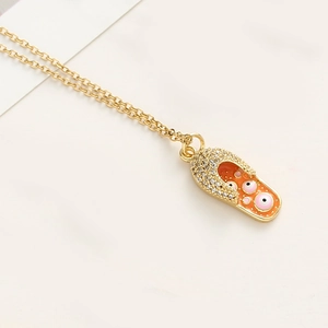 Détail du pendentif tong dorée avec émail orange et motif œil maléfique