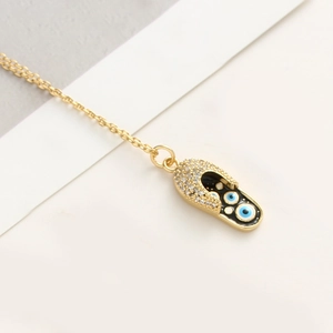 Macro d'un pendentif sandale doré avec émail œil protecteur et oxydes de zirconium