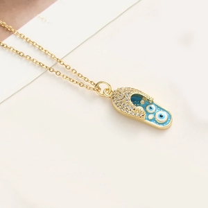 Vue macro du pendentif tong en or avec émail bleu œil maléfique et strass scintillants