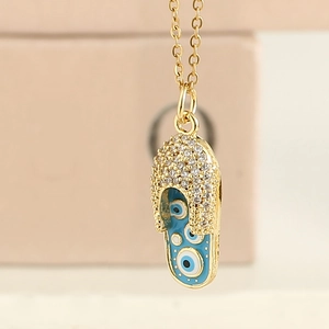 Détail du pendentif tong dorée avec émail bleu œil protecteur et cristaux pavés