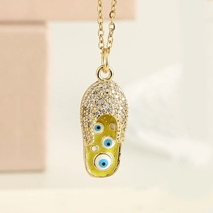 Macro d'un pendentif chaussure œil protecteur doré avec émail jaune et micro-zircons