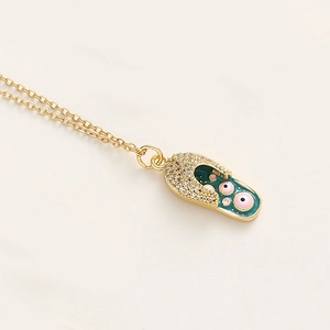 Détail du collier chaîne dorée avec pendentif chaussure en émail vert et zircons brillants