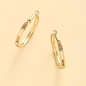 Détail de créoles dorées ornées de zircons multicolores et d'un design ajouré sophistiqué