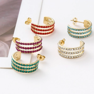 Detail of C-shaped gold stud earrings with multi-colored crystals in three rows