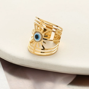 Golden evil eye wide ring with hollowed multi-layer design on a white marble display