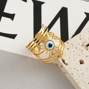 Detailed close-up of hollow gold Evil Eye ring on natural beige travertine stone
