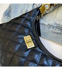 Detailed view of black quilted leather texture and vintage gold buckle on dumpling bag