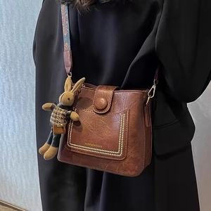 Vintage PU Leather Bucket Bag For Women With Wide Woven Shoulder Strap And Rabbit Pendant Studded Design Crossbody Handbag