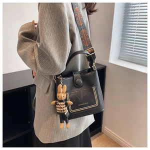 Retro black leather bucket bag with gold rivets, colorful strap, and rabbit pendant