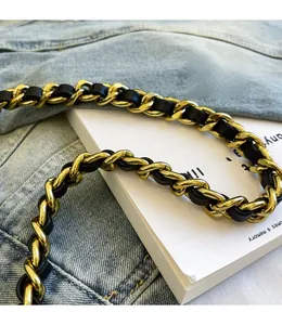 Close-up of golden metal chain handle with black leather weaving on a quilted bag