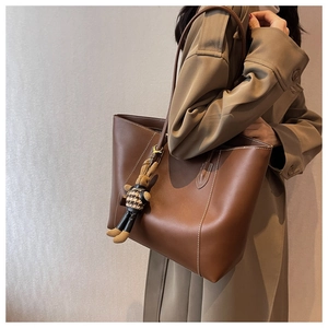 Détail d'un cabas vintage marron avec surpiqûres blanches et pendentif lapin ludique