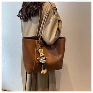 Grand sac cabas marron avec surpiqûres et breloque lapin porté sur un mannequin