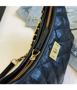 Detail of black quilted leather with gold zipper and chain strap on hobo bag