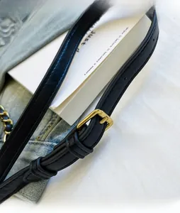 Detailed macro view of an adjustable black leather shoulder strap with a gold metal buckle