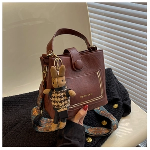 Vintage dark brown bucket bag with ethnic strap and rabbit charm held in hand
