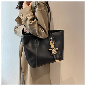 Détail d'un sac cabas noir avec surpiqûres blanches et charmant pendentif lapin