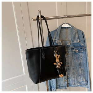 Détail d'un sac cabas en cuir noir avec surpiqûres blanches et pendentif lapin peluche