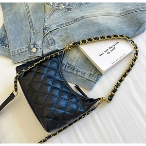Detailed macro view of black quilted leather crescent bag with gold chain strap detail