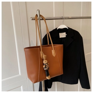 Détail d'un cabas en cuir marron avec surpiqûres blanches et breloque lapin mignon