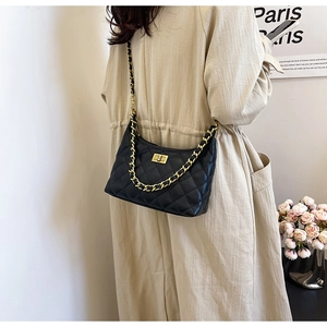 Detailed view of black quilted chain bag with gold metal buckle and woven strap design