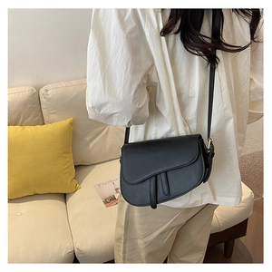 Side view of a black vintage saddle bag with decorative pendant worn by a model