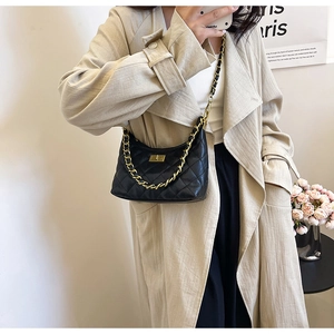 Detailed view of black quilted leather shoulder bag with golden chain and turn-lock closure