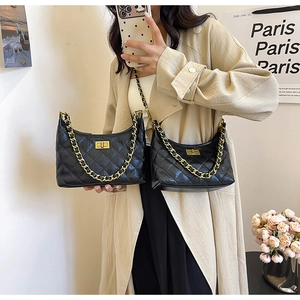 Detailed view of black quilted chain bag with gold metal hardware and turn-lock closure
