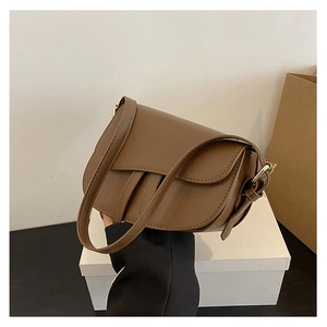 Detail view of a vintage brown leather saddle bag with adjustable shoulder strap and metal buckle