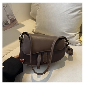 Detailed close-up of a dark brown faux leather saddle bag with gold-tone hardware detail