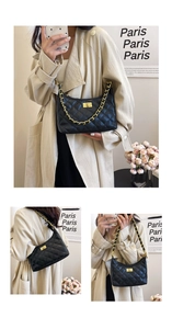 Detail of black quilted leather shoulder bag with gold chain and square metal lock closure