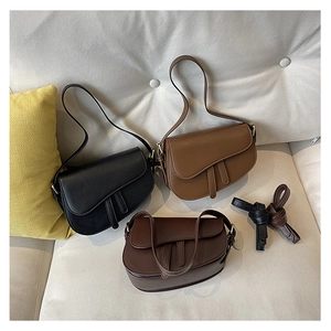 Three saddle bags in black, caramel and dark brown colors shown on a sofa