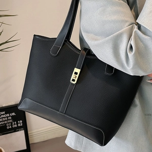 Black pebble grain leather tote bag with white stitching and gold clasp on model