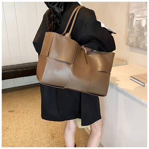 Detail of large dark brown woven tote bag with leather texture and thin shoulder straps