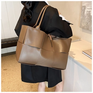Detailed view of brown woven tote bag featuring wide leather straps and large capacity