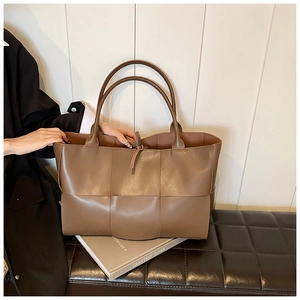 Detailed close-up of wide-weave brown leather tote bag showing intricate texture