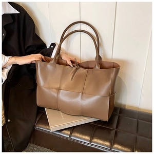 Detail of dark brown woven leather tote bag texture and straps on a bench