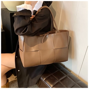 Detail of dark brown woven tote bag showing premium PU leather texture and shoulder strap