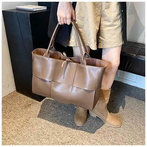 Close-up of a dark brown large woven tote bag with premium matte leather texture