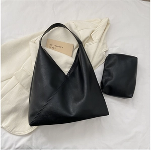 Detail of vintage soft black leather tote bag with matching inner pouch on white blazer